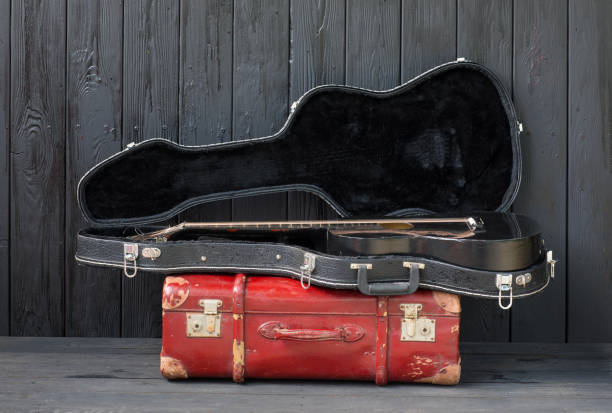 istock black guitar and a suitcase against a black wooden background 1155282490