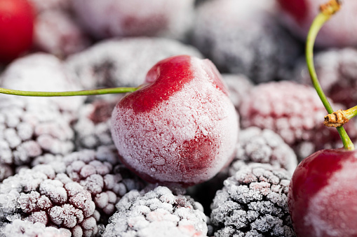 Extreme closeup of frozen mulberries and cherries.