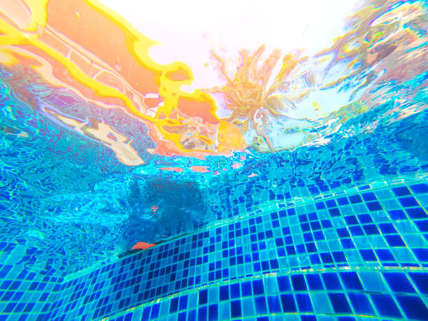 A smiling child swimming underwater in a pool in goggles