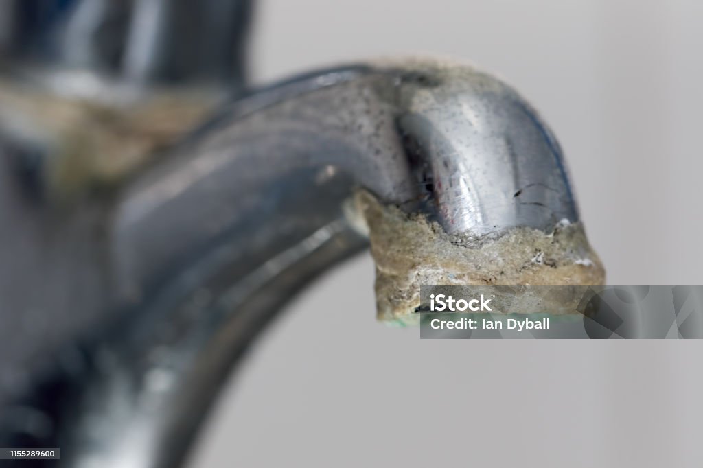 Close-up of limescale build-up. Selective focus on hard water deposit. Close-up of limescale build-up. Selective focus on hard water deposit on old tap spout. Chrome kitchen or bathroom faucet with crusty calcium carbonate needing descaler. Water Stock Photo