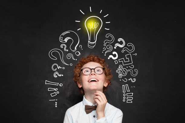 istock Happy kid looking at lightbulb on blackboard background. Brainstorming and idea concept 1155294412