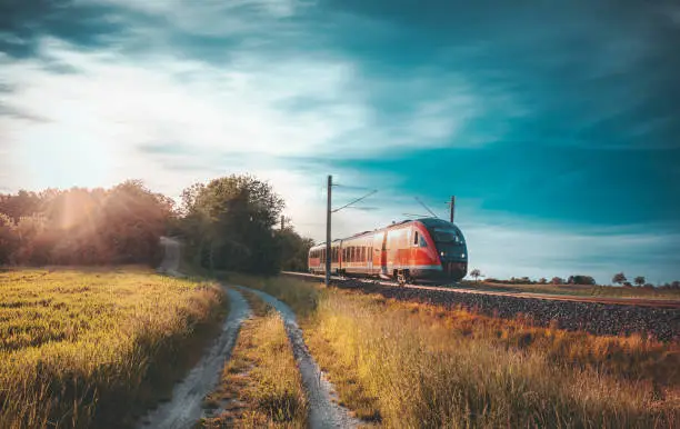 Photo of Red German train traveling on railway tracks through nature