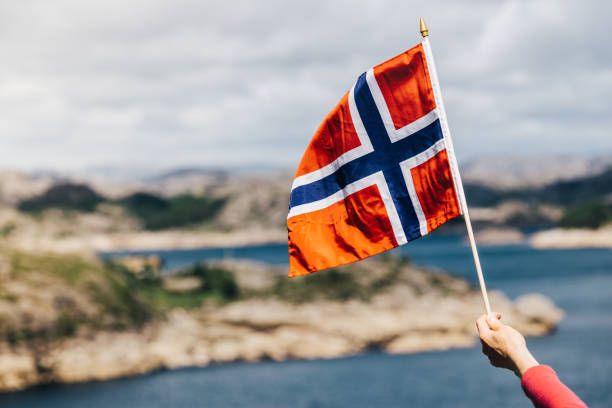 istock Tourist with norwegian flag on sea coast 1155298082