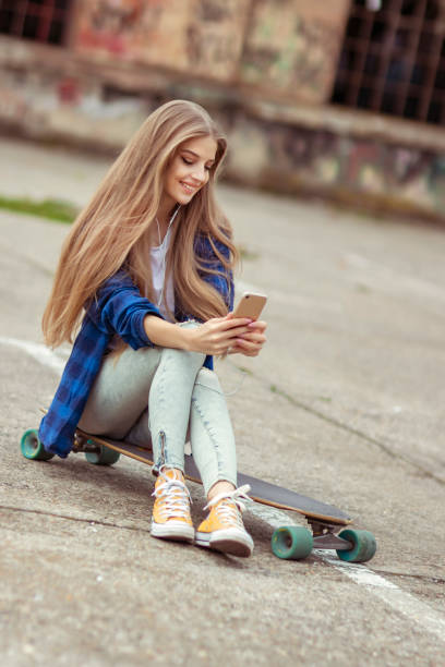 istock Female Skateboarder is Using a Mobile Phone in the Street 1155308867