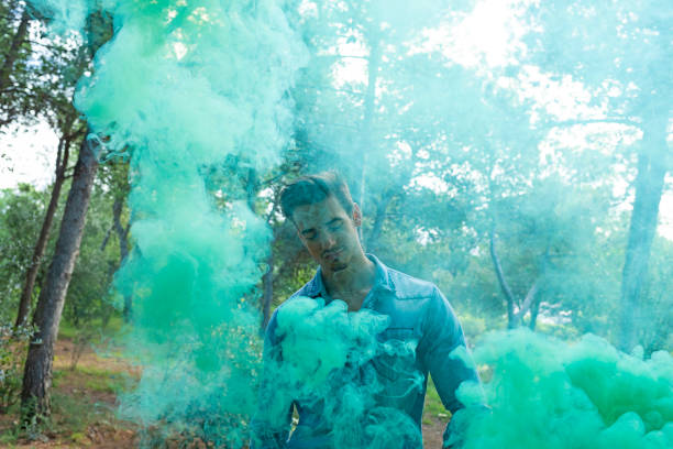 istock Young bare man in colored smoke outdoors in the forest 1155316765