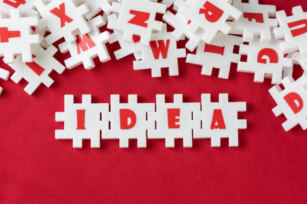 istock Business idea, creativity and imagination concept, abundance white puzzle jigsaw with alphabets combine word IDEA and other letter pieces pouring from glass bottle on red fabric background 1155316788