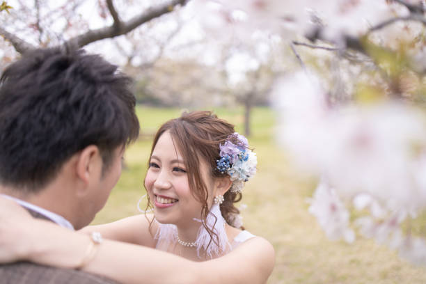 istock Happy bride and groom looking at each other under cherry blossom 1155321168