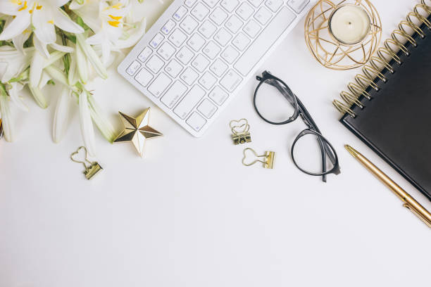 istock Flat lay home office desk. Female workspace with computer keyboard, golden accessories, glasses, black diary 1155322713