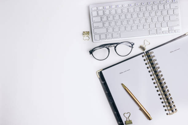 istock Flat lay home office desk. Female workspace with computer keyboard, golden accessories, glasses, black diary 1155322725