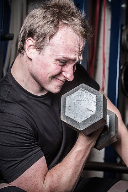istock Young man doing dumbbell curls in a Connecticut gym. 1155327043