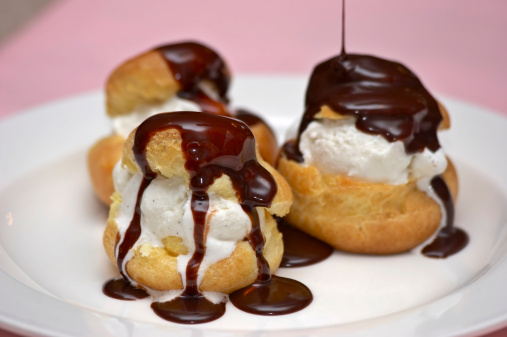 Some profiteroles, covered with chocolate syrup.