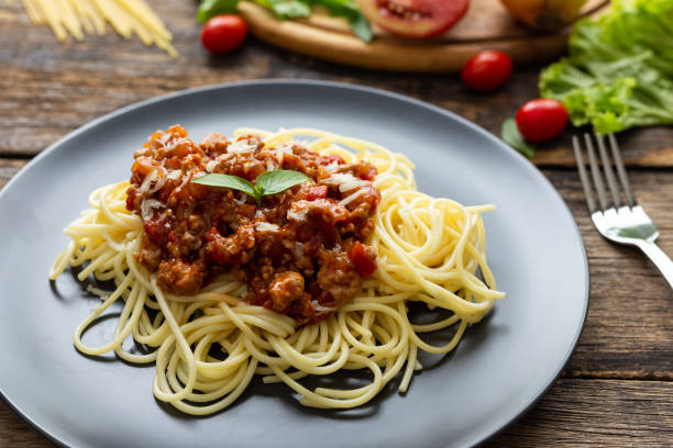 istock Spaghetti on black plate on wooden background. top view 1155339909
