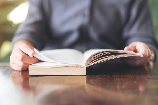 istock a woman holding and reading a vintage novel book 1155341469