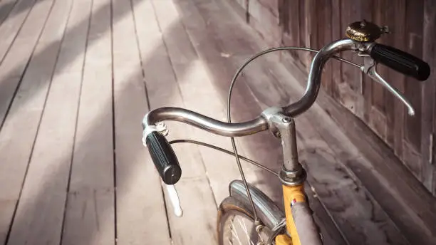 Photo of Bicycle handle bar close up. Vintage filter wooden floor background