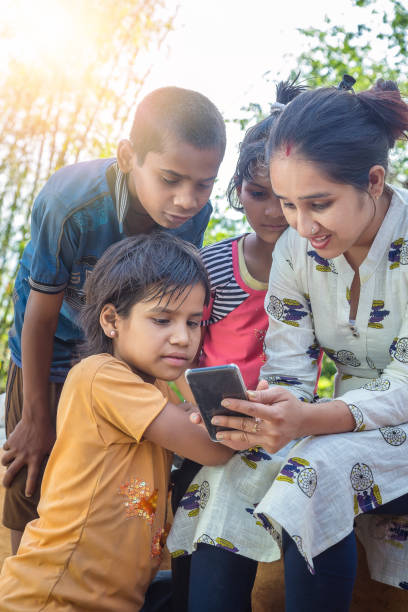 les femmes ouvrières d’ong avec des enfants utilisant le téléphone portable - global village photos et images de collection