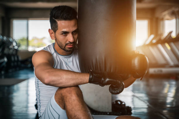 istock Boxer training on a punching bag in the gym 1155349838