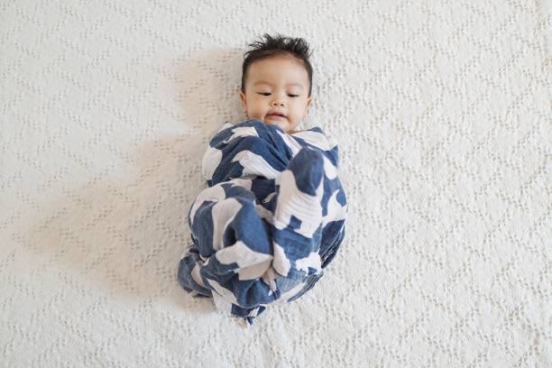 Baby swaddled with a blue blanket stock photo