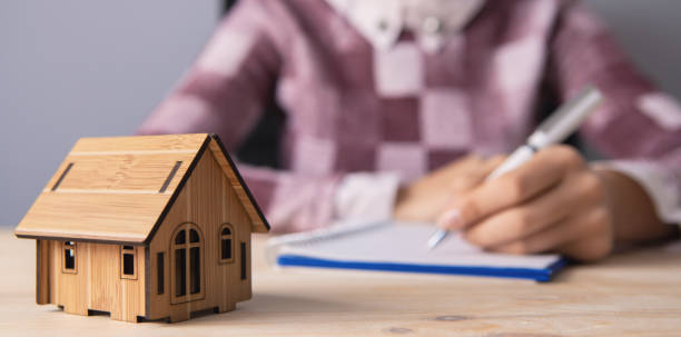 istock young woman with a dwelling house and documents; real estate agent 1155355379