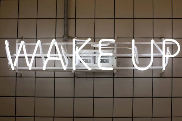 istock A wake-up with a neon sign hanging on the wall 1155360447