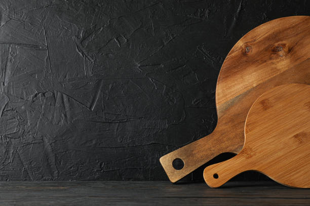 istock Cutting boards on wooden table against black background, space for text 1155363907