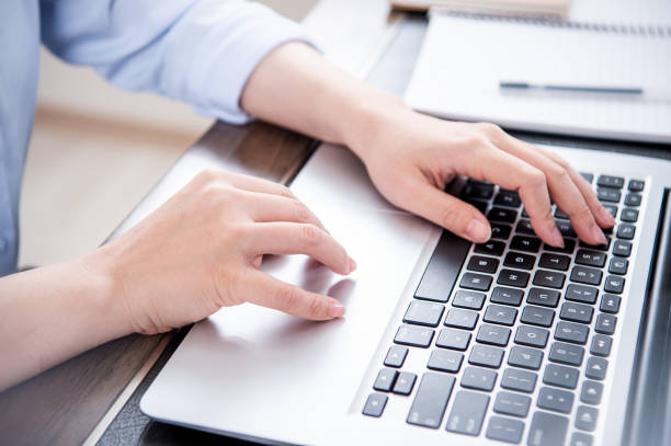 istock Business concept. Woman in blue shirt typing on computer with coffee on office table, backlighting, sun glare effect, close up, side view, copy space 1155367160