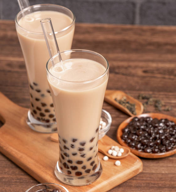 istock Popular Taiwan drink - Bubble milk tea with tapioca pearl ball in drinking glass and straw, wooden table gray brick background, close up, copy space 1155367236