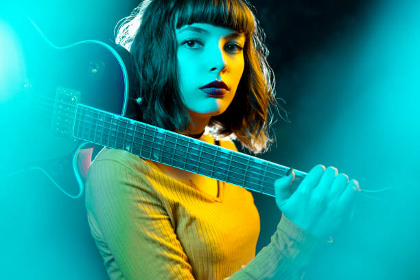 belle jeune femme de hipster avec les cheveux bouclés avec la guitare rouge dans les lumières de néon. musicien de rock joue de la guitare électrique. concept de style des années 90. - musicien photos et images de collection