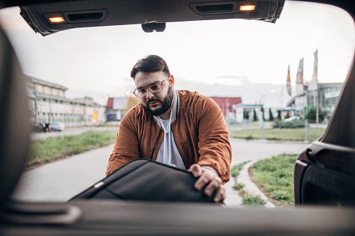 Man packing luggage suitcase in his car ready for road trip
