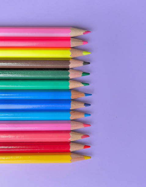 top view on colorful pencils in line on mauve background