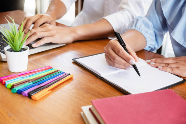 istock Two adult people working together with documents in library. Education concept. 1155372318