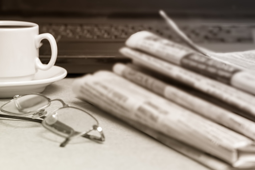 The concept of news. A Cup of morning coffee, Newspapers, glasses, laptop on the desktop.
