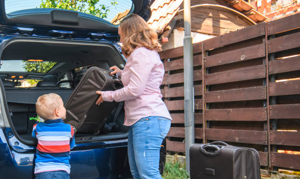 istock Mother and son packing backpacks and suitcases into a car trunk 1155375912