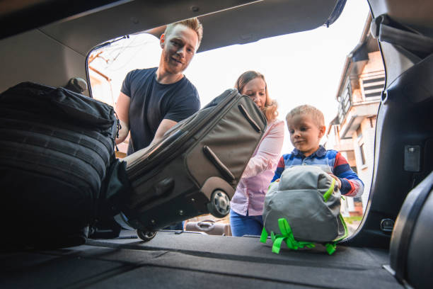 istock Family packing backpacks and suitcases into a car trunk 1155375920