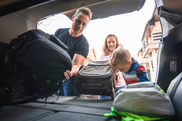 istock Family packing backpacks and suitcases into a car trunk 1155375926