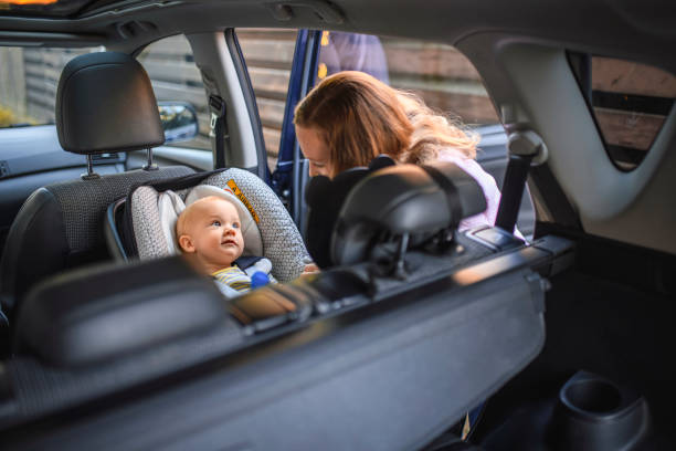 mother putting her son in a car safety seat - offspring child lying on back parent imagens e fotografias de stock