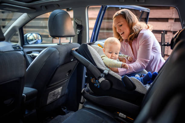 mother putting her son in a car safety seat - offspring child lying on back parent imagens e fotografias de stock