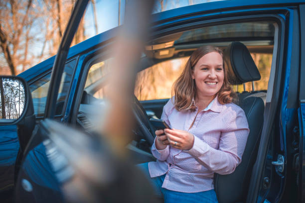 istock Young woman sitting in a car and texting 1155376034