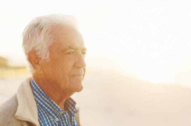 istock Serene senior man stands on misty beach in winter sunlight 1155376721