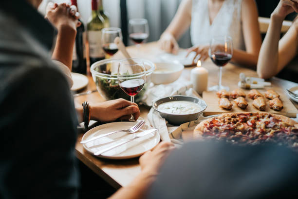 Group of joyful young Asian man and woman having fun, enjoying food and wine across table during party Group of joyful young Asian man and woman having fun, enjoying food and wine across table during party dining table photos stock pictures, royalty-free photos & images