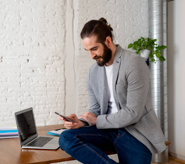 istock Happy successful entrepreneur checking mobile phone while working in modern cool home office. Lifestyle portrait of freelancer owner of small company In successful people and business concept. 1155381883