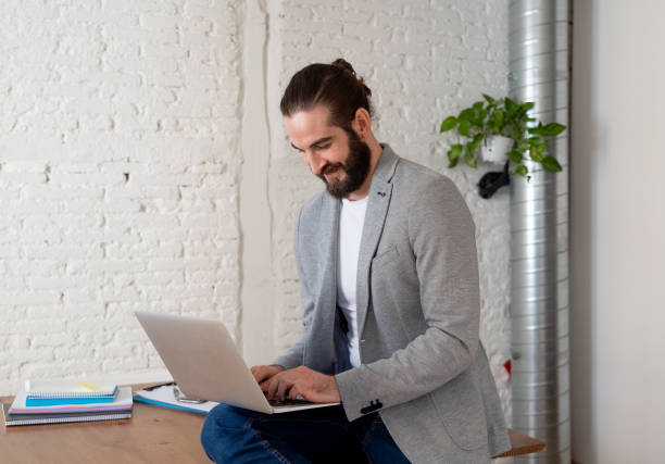 istock Successful hipster entrepreneur working on laptop in his modern studio home office. Looking happy and confident with own business success. In People startup and successful young businessmen concept. 1155382056