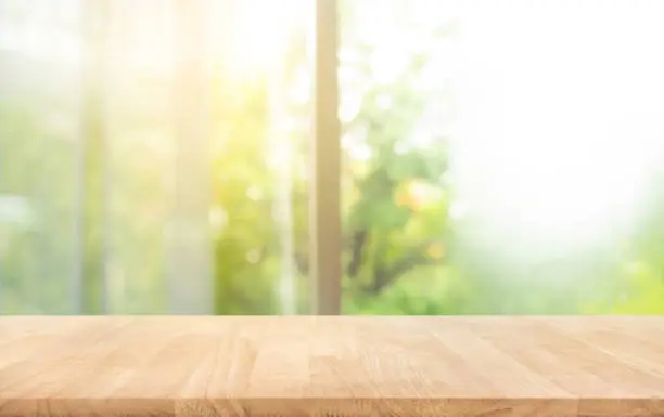 Wood table top (counter bar) on blur of window with beautiful garden in morning background.Horizontal banner size for disign key visual layout of product