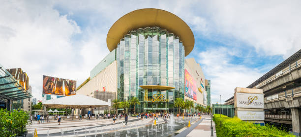 Bangkok Siam Paragon downtown shopping centre Pathum Wan panorama Thailand Shoppers walking through the plaza outside the Siam Paragon shopping mall in the Pathum Wan downtown district of Bangkok, Thailand’s vibrant capital city. thailand mall stock pictures, royalty-free photos & images