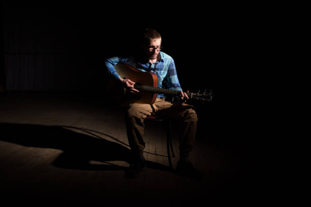 istock Young musician playing the guitar on dark background 1155397384