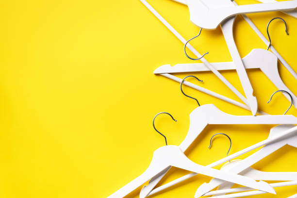istock White clothes hangers on yellow background with copy space. Flat lay. Top view. Minimalism style. Creative layout. Fashion, store sale, shopping concept. Banner for feminine blog 1155398133