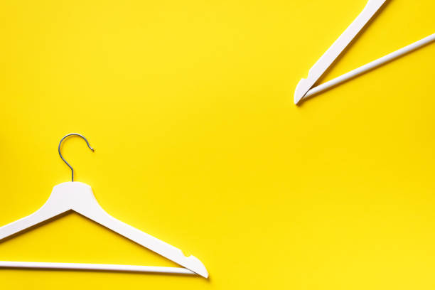 istock White clothes hangers on yellow background with copy space. Flat lay. Top view. Minimalism style. Creative layout. Fashion, store sale, shopping concept. Banner for feminine blog 1155398145