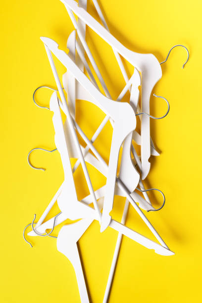 istock White clothes hangers on yellow background with copy space. Flat lay. Top view. Minimalism style. Creative layout. Fashion, store sale, shopping concept. Banner for feminine blog 1155398185