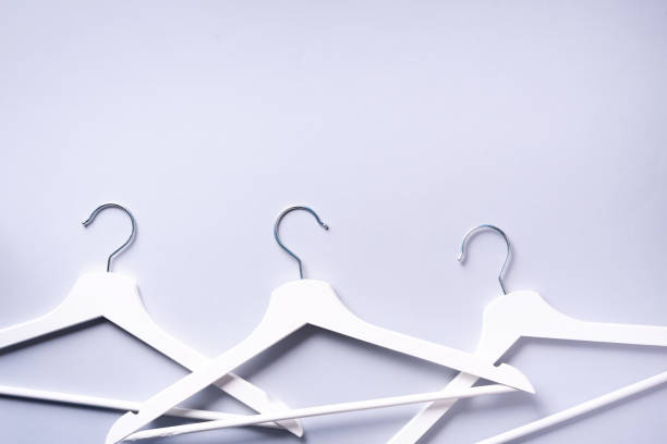istock White clothes hangers on grey background with copy space. Flat lay. Top view. Minimalism style. Creative layout. Fashion, store sale, shopping concept. Banner for feminine blog 1155398290
