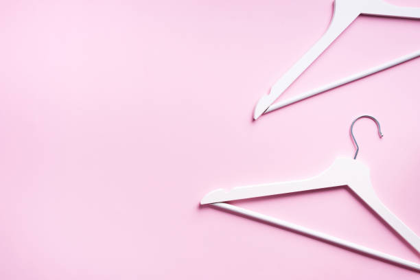 istock White clothes hangers on pink background with copy space. Flat lay. Top view. Minimalism style. Creative layout. Fashion, store sale, shopping concept. Banner for feminine blog 1155398363