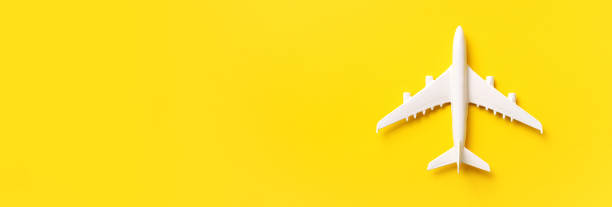 istock White plane, airplane on yellow color background with copy space. Top view, flat lay. Minimal style design. Travel, vacation concept. Banner. 1155398656